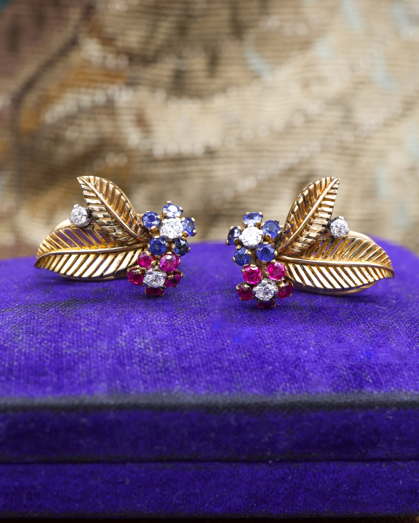 A very fine pair of 18ct Yellow & White Gold (tested), Retro, Clip Earrings, a Stylised Foliate Design set throughout with Diamonds, Burma Rubies & Sapphires. Circa 1940