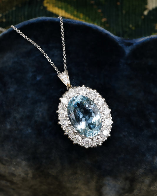 A fine 18 ct. White & Yellow Gold (tested) Oval Aquamarine and Diamond Cluster Pendant. Mid - Late 20th Century.