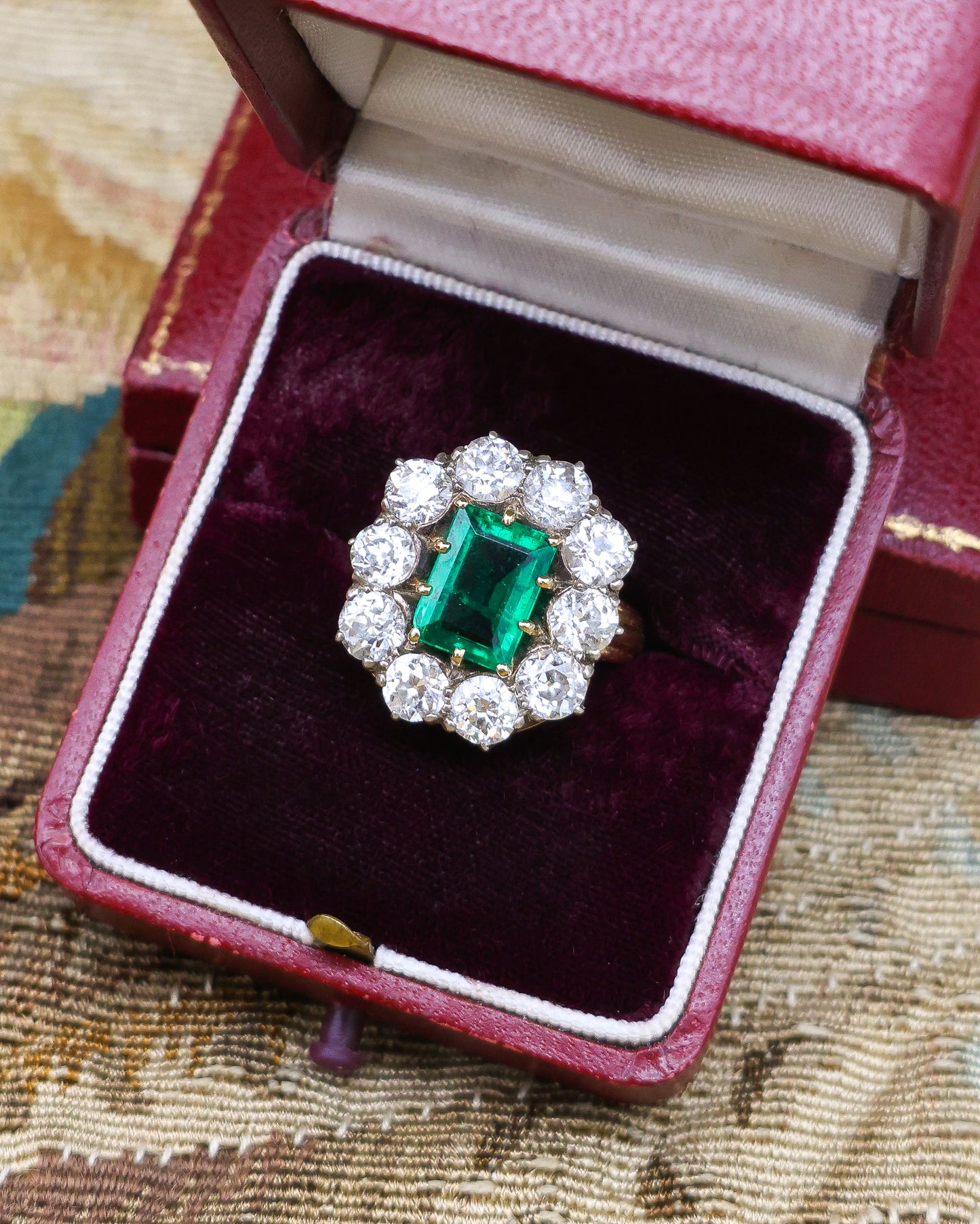 An exceptional Emerald and Diamond Cluster Ring. Colombian Emerald, 2.60 carats approximately, minor oil, with ten Old Cut Diamonds, approximately 5.00 carats (unweighed).  Ring circa 1890.