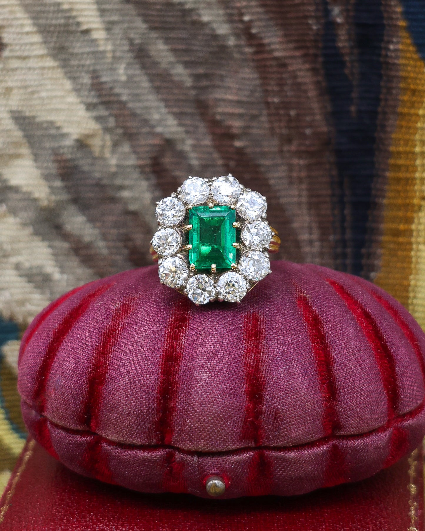 An exceptional Emerald and Diamond Cluster Ring. Colombian Emerald, 2.60 carats approximately, minor oil, with ten Old Cut Diamonds, approximately 5.00 carats (unweighed).  Ring circa 1890.