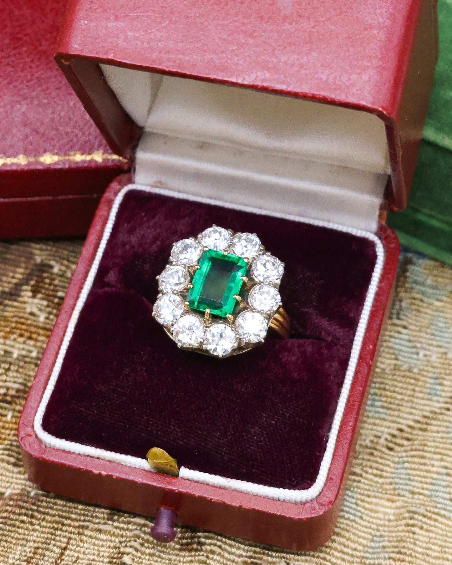 An exceptional Emerald and Diamond Cluster Ring. Colombian Emerald, 2.60 carats approximately, minor oil, with ten Old Cut Diamonds, approximately 5.00 carats (unweighed).  Ring circa 1890.