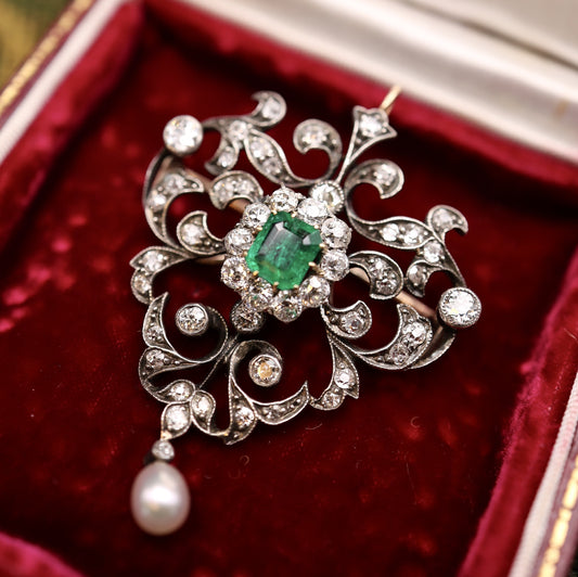 A very fine Antique Edwardian Pendant/Brooch, a central Emerald & Diamond Cluster within a foliate stylised Heart Shaped Diamond Set frame suspending a Pear shaped Natural Pearl. Circa 1890